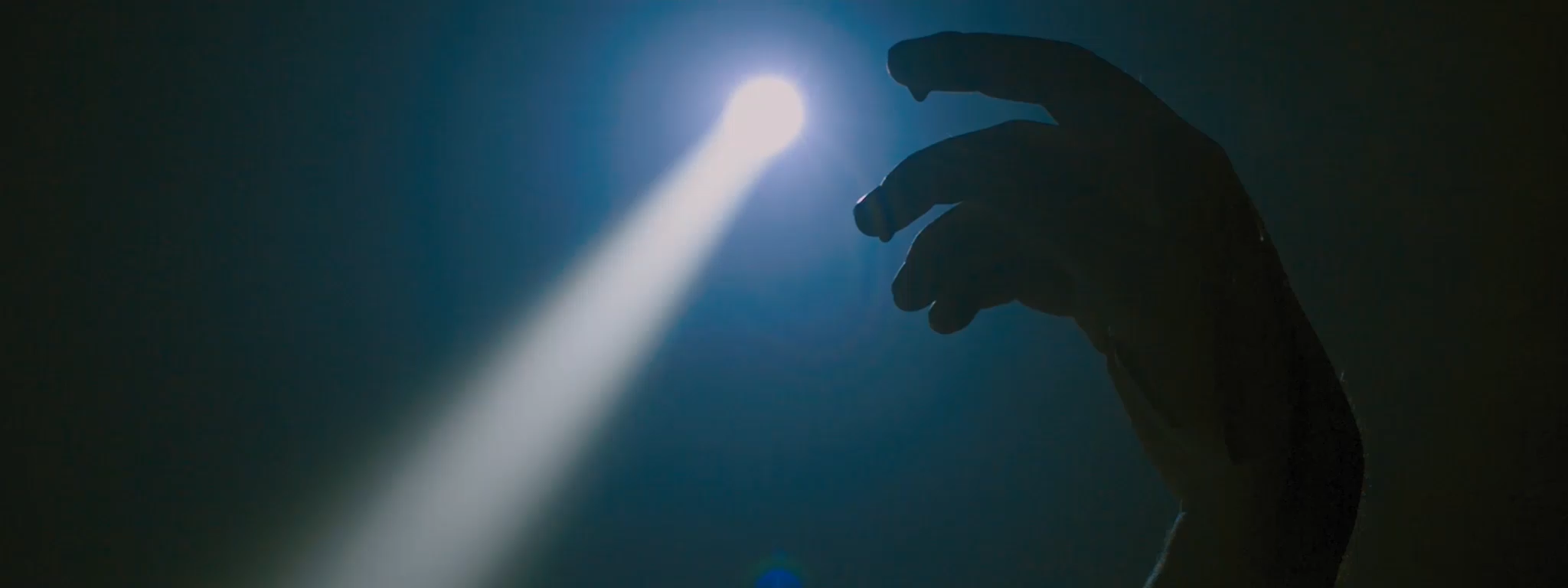 Another shot from the trailer, featuring a hand rising out from the bottom of the screen, and a spotlight created from a headlamp.